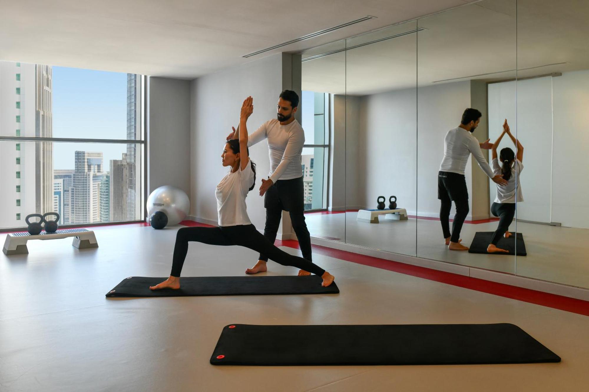 Dusit Doha Hotel Zewnętrze zdjęcie A personal trainer assisting a woman with a yoga workout